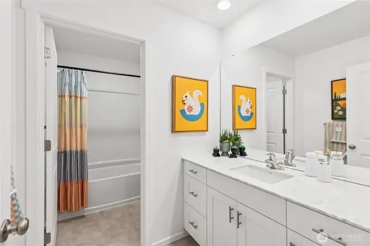 Hall bathroom with quartz top vanity and separate door to toilet and shower for convenience. Actual home is under construction and finishes, colors, and materials may vary. See site agent for details.