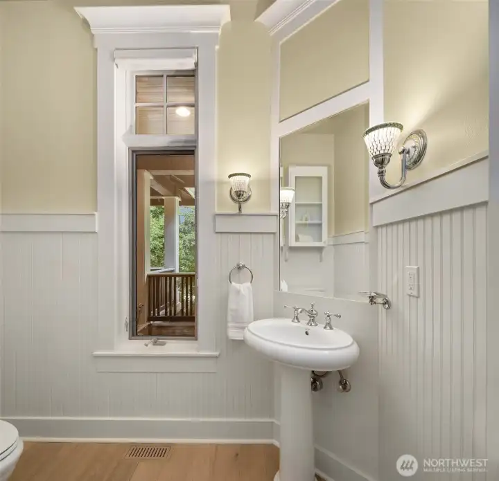 A stylishly detailed powder room with pedestal sink, beadboard, and classic millwork - refined down to every finish.