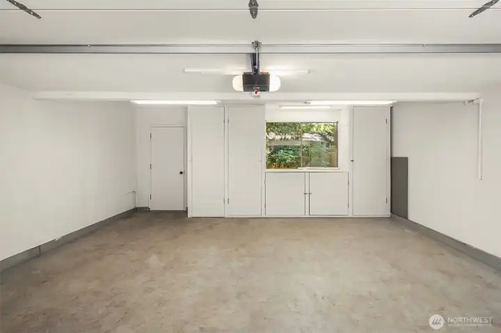 Two-car garage with built-in storage solutions and access to the backyard.