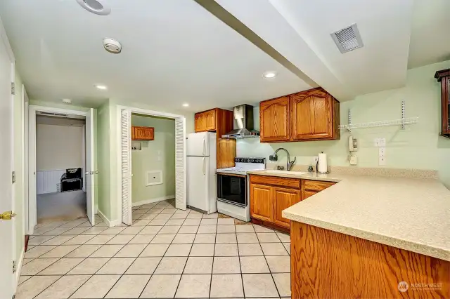 Lower Kitchen with tile flooring, oak cabinetry, stainless hood fan, walk in pantry and laundry area for a full sized washer and dryer. Hyper insolated from the rest of the home with sound block sheetrock airspace separator.