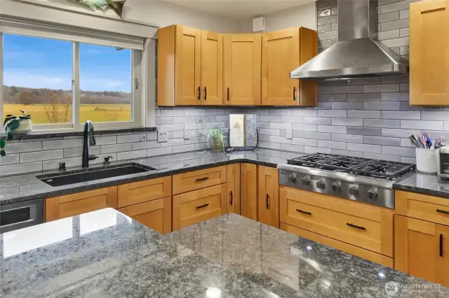 Gas stove, custom cabinets, and glass tile backsplash