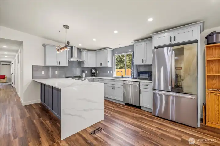 Kitchen with waterfall style peninsula. Vaulted Ceilings and great interior Lighting throughout. With Stainless Steel Appliances.