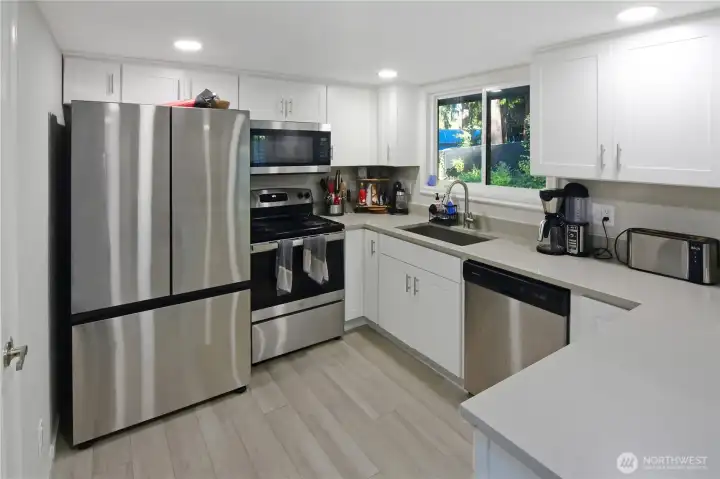 Newly remodeled kitchen with stainless steel appliances, brand-new refrigerator, durable LVP flooring, and modern stainless sink—updated Bonney Lake home.