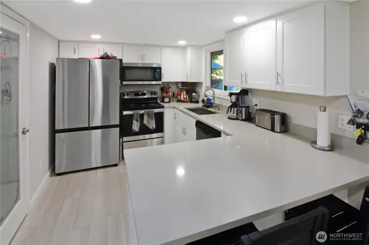 Kitchen view with quartz countertops, breakfast nook seating, and walk-in pantry with glass door—stylish and functional Bonney Lake rambler kitchen.