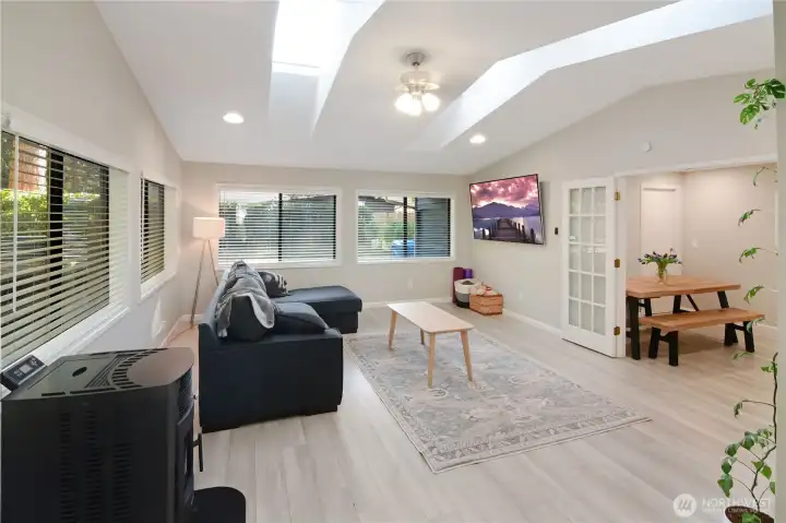 Spacious family room with four skylights, abundant natural light, and new pellet stove for efficient heating—bright and inviting space overlooking the dining area.