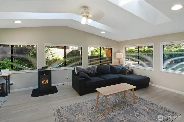 Family room with vaulted ceiling, multiple skylights, LVP flooring, and surrounding windows—light-filled Bonney Lake rambler living space.