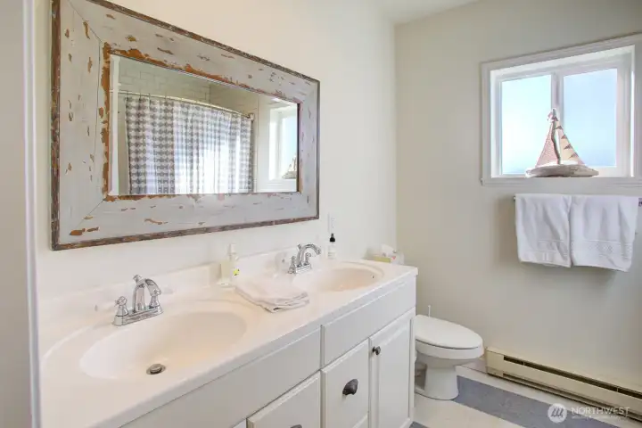 The bathroom has double vanities and a tile tub/shower.