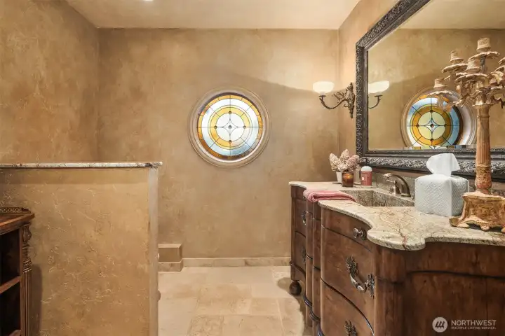 Showcasing artisan-level details, the powder room boasts a rare stained glass piece that acts as a stunning focal point.