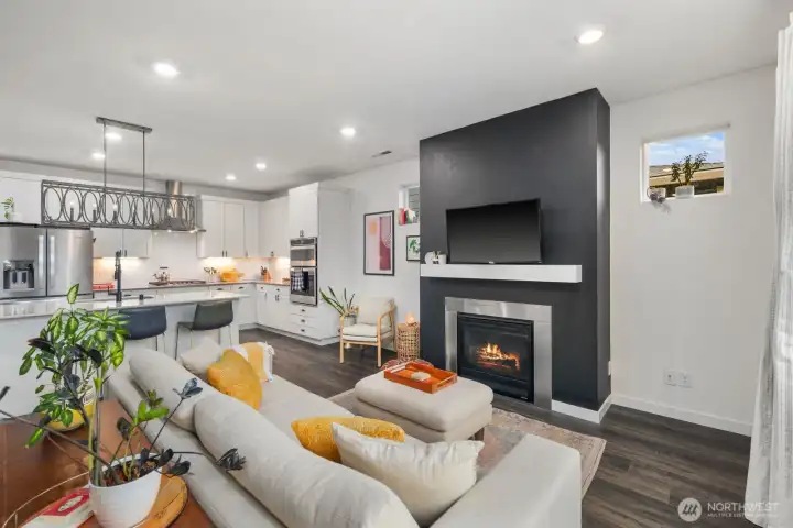 Open concept great room showing the living area flowing into the kitchen with center island, stainless steel appliances, and recessed ceiling lighting.