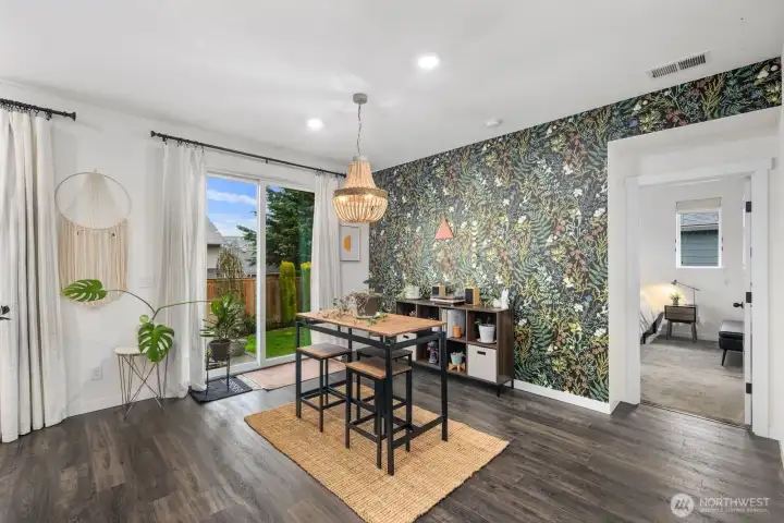 Dining area filled with natural light, featuring sliding glass door access to the backyard and a striking botanical accent wall that adds personality and warmth to the space.