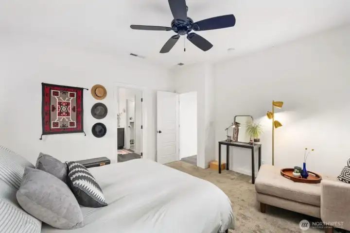 Bedroom perspective looking toward the doorway and ensuite access, featuring bright natural light, ceiling fan, and a cozy, airy atmosphere.