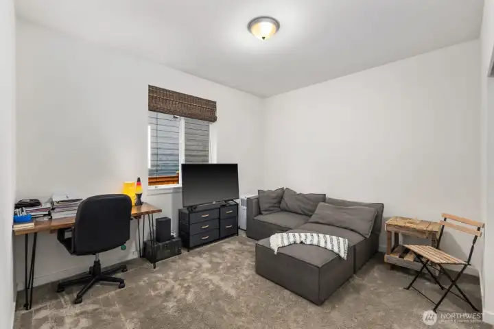 Flexible bonus room set up as a lounge and workspace, featuring a window for daylight and plenty of room for a desk, media setup, or creative space.