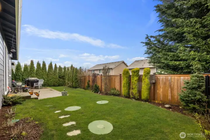 Private backyard with green lawn, wood privacy fencing, and landscaped perimeter plantings, creating a peaceful outdoor space to relax or entertain.