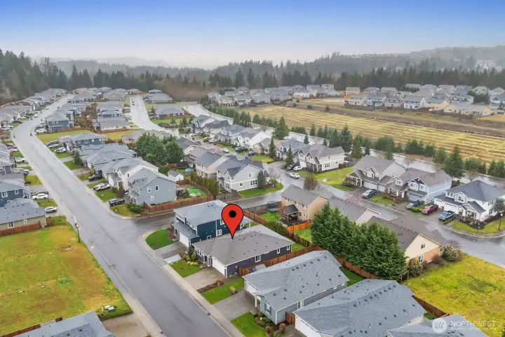 Drone perspective highlighting the home’s location along a quiet residential street, surrounded by well-kept homes and neighborhood green space.