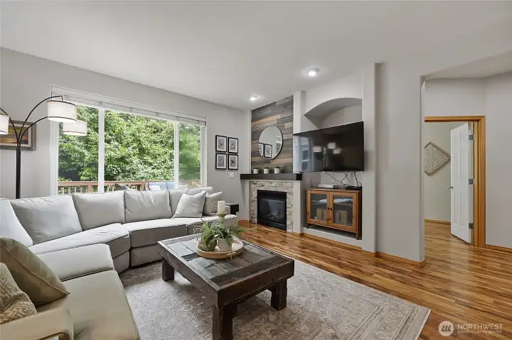 Cozy up in the family room featuring a stunning floor-to-ceiling fireplace with reclaimed wood accents and a rustic mantel. Large picture windows frame peaceful views of the private backyard greenery. Cozy up in the family room featuring a stunning floor-to-ceiling fireplace with reclaimed wood accents and a rustic mantel. Large picture windows frame peaceful views of the private backyard greenery.