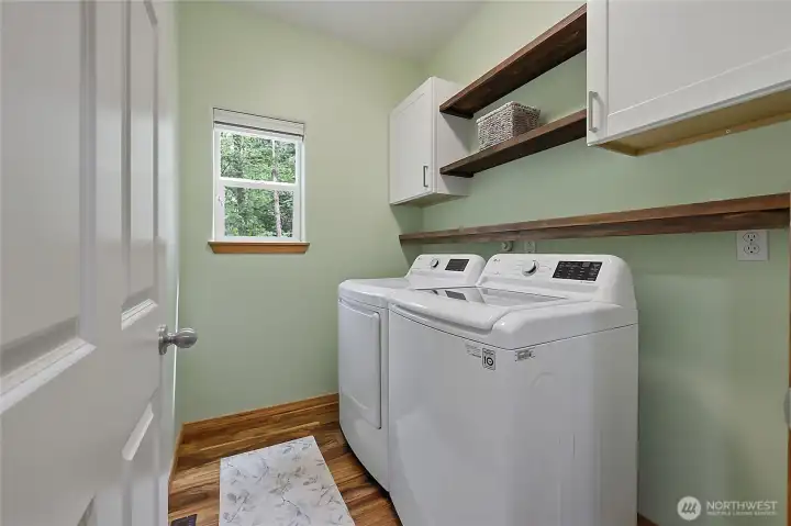 The dedicated laundry room is a model of efficiency, complete with built-in cabinetry for organization, a convenient folding counter, and updated appliances. The dedicated laundry room is a model of efficiency, complete with built-in cabinetry for organization, a convenient folding counter, and updated appliances.
