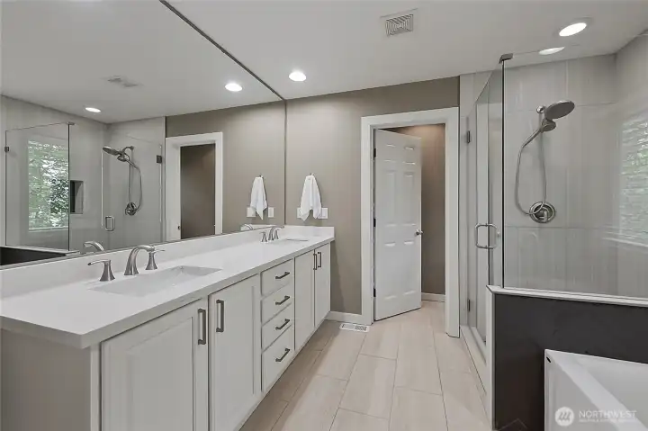 Luxurious five-piece bath with a dedicated makeup vanity, deep soaking tub, and custom-tiled walk-in shower. Luxurious five-piece bath with a dedicated makeup vanity, deep soaking tub, and custom-tiled walk-in shower.