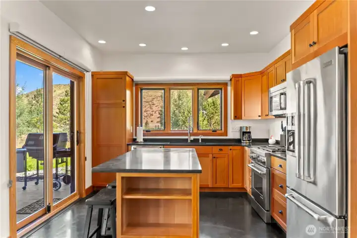 The kitchen is appointed with black soapstone countertops, stainless Jenn-Air appliances, and a tile backsplash.