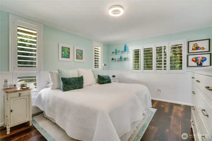 Serene primary suite: wainscoting, plantation shutters & rich plank flooring. Serene primary suite: wainscoting, plantation shutters & rich plank flooring.