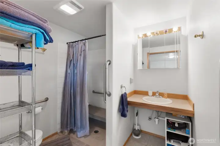 3/4 ensuite bathroom handicap accessible with handrails and a shower bench