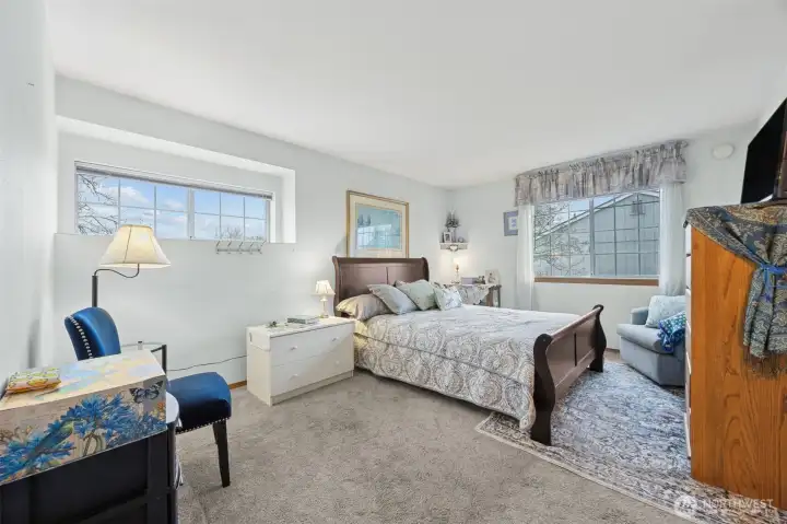 Spacious primary suite with windows for natural lighting and even a small sitting area for a cozy chair to enjoy a nice book.