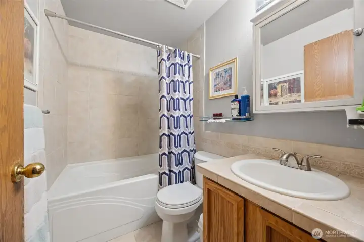 Upstairs guest bathroom with artistic tile surround that flows nicely into behind the toilet & sink! Soaking tub is oversized!