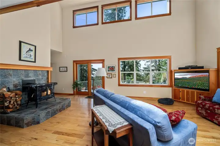 light filled living room with wood stove and french doors to deck & fenced yard
