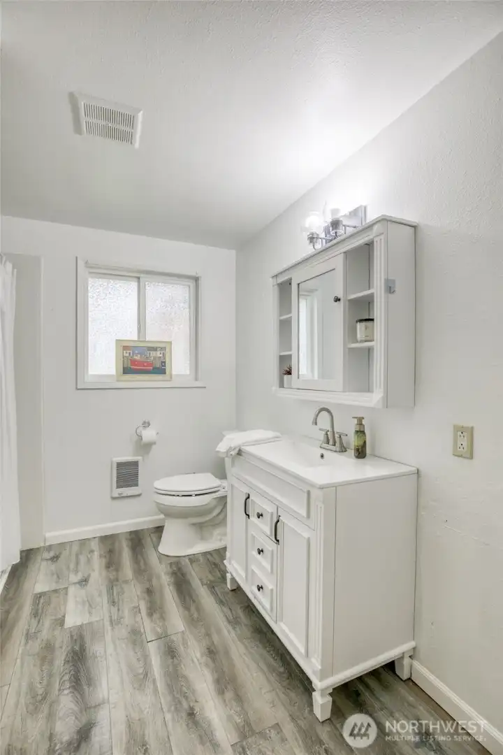 Updated bath features modern flooring, vanity, and lighting