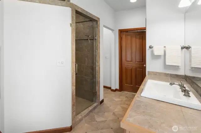 Luxurious custom tiled walk-in shower with glass door. Tiled counter and floors. Separate potty room.