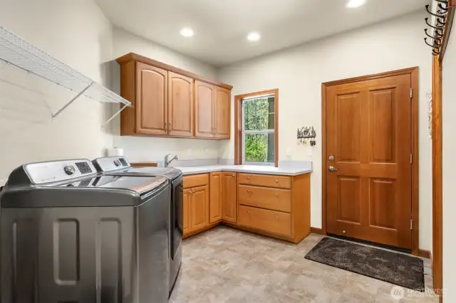 Over-sized laundry room provides access between the garage and the home. Cabinets, counter space and utility sink. Washer and dryer stay! And a half bath attached!