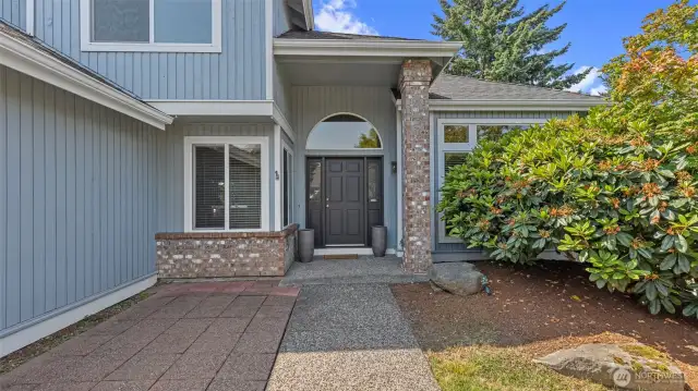 Walkway to main entrance. So welcoming between the front patio, covered front porch, brick column and arched window.