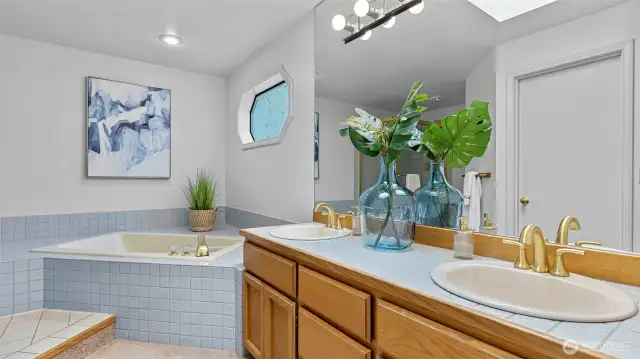 Spacious, elegant and relaxing primary bathroom with a deep soaking tub, doubled sink counter, and long shower stall.