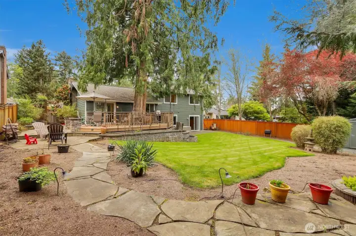 Park-like back yard with stone walkway, garden space, and water feature.