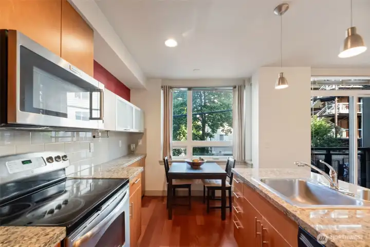 Spacious kitchen with granite countertop and eating area wtih walls of windows and lots of cabinetry for storage