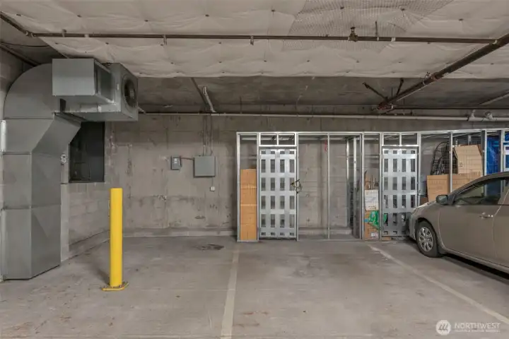 Oversized assigned parking space in common garage with large storage unit in front of the garage space