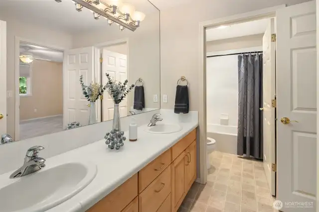 Full bath with dual sink vanity and tub/shower combo.