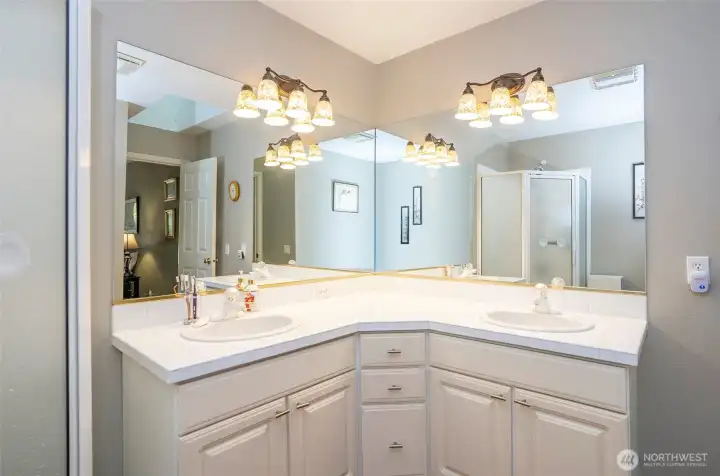 Beautifully appointed primary bath with double vanity and tile surfaces,