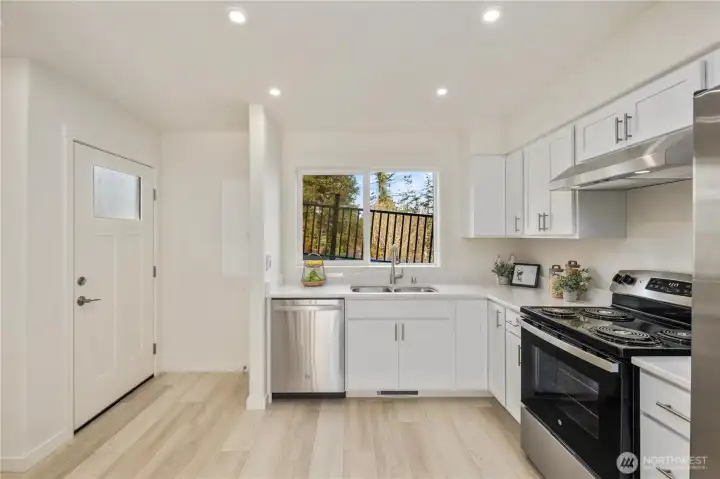 Functional kitchen layout with stainless appliances, modern cabinetry, and window views bringing in natural island light.