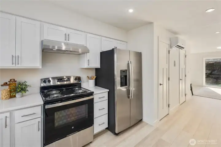 Contemporary kitchen with electric range, stainless refrigerator, and streamlined cabinetry designed for low-maintenance island living.
