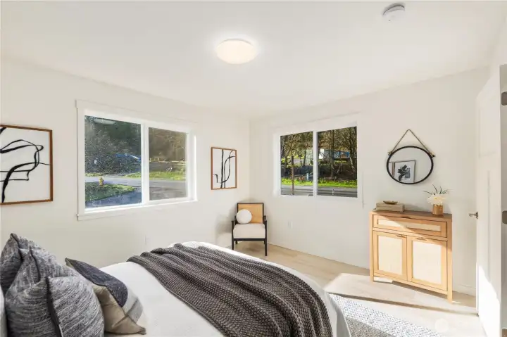 Upper-level bedroom with large window, natural light, and clean modern finishes consistent with new construction design.