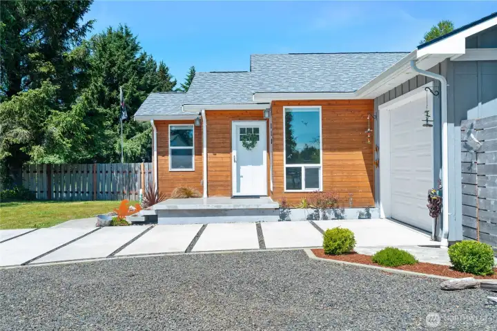 Front poured concrete porch, stained wood siding and lots of parking