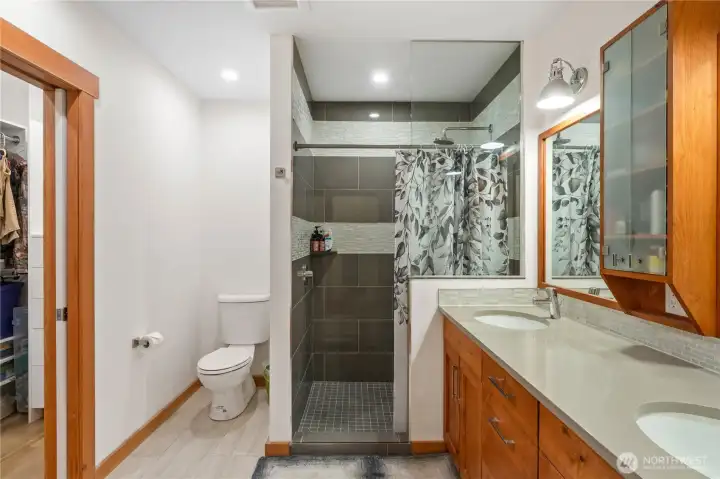 Primary bathroom with walk-in tiled shower, double vanity and built in storage