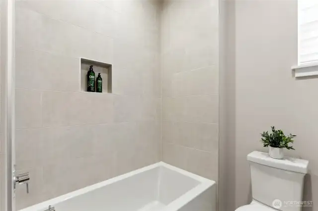 Upstairs hall bathroom with tub and full height tile surround.