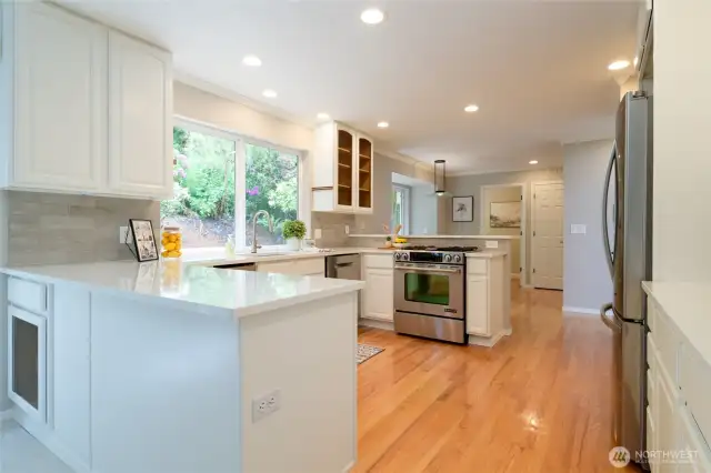 The kitchen is noteworthy with it's clean lines, classic cabinetry, and updated finishes to create a fresh, inviting atmosphere, perfectly complemented by the natural light that streams in from adjacent living space. Lovely views from the large windows overlook the back deck and gardens.