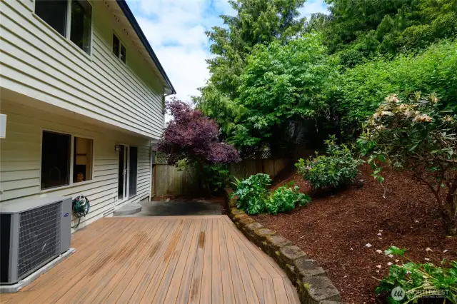 Love the outdoors but dislike mowing the grass? You'll appreciate the natural landscape of this back yard. The Duradeck provides a generous space to  relax or entertain. The top of the property flattens out. Originally, the owner planned to put in steps and create a patio/fire pit at the top to enjoy views of Puget Sound and the Olympic Mountains. New Air conditioning unit to left of frame. Slab ready and wired for a hot tub!