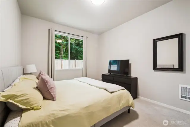 Primary bedroom looks out to private backyard and many trees.