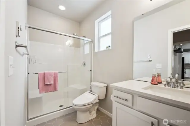 Primary suite bathroom has walk-in shower, tile flooring, upgraded quartz countertop with undermount sink