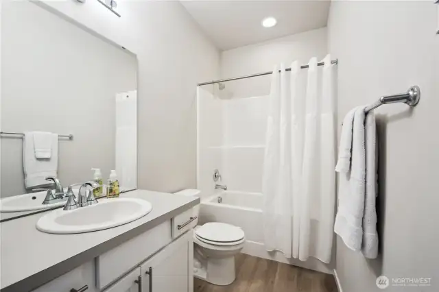 Full bathroom with generous counter space, huge mirror, and own linen closet