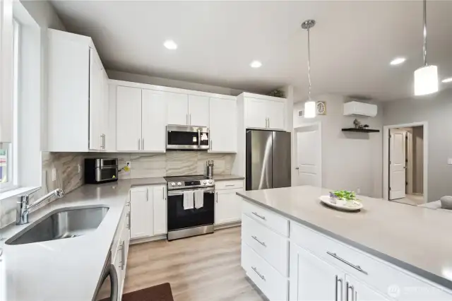 Tile backsplash, sink beneath large picture window, and ample lighting are more welcome features in this working kitchen.
