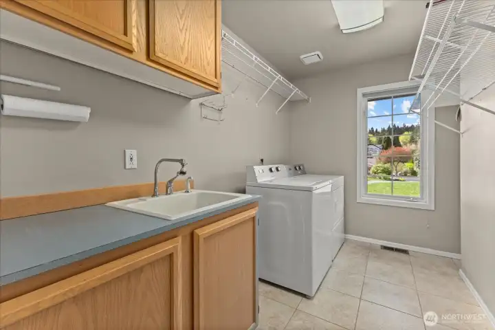 Well-appointed laundry room with utility sink, workspace and storage